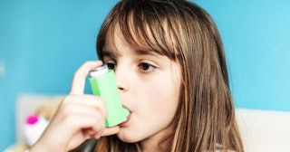 Portrait close up of little girl child using asthma inhaler during pandemic