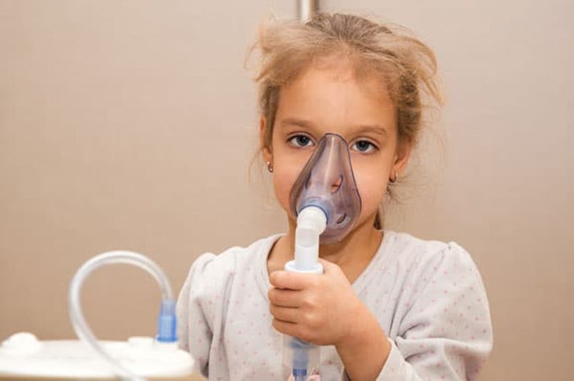 A 5-year-old child inhales medication using a nebulizer.