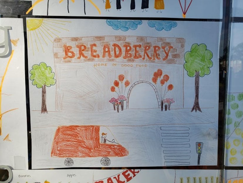 A child's drawing of a rebuilt Breadberry store with orange balloons and flowers at the entrance