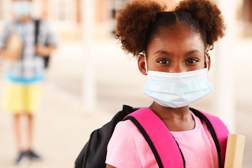 girl on school campus. She wears a mask for COVID-19