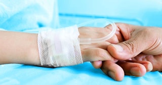 Close-Up Of Hand Holding Patient At Hospital Bed