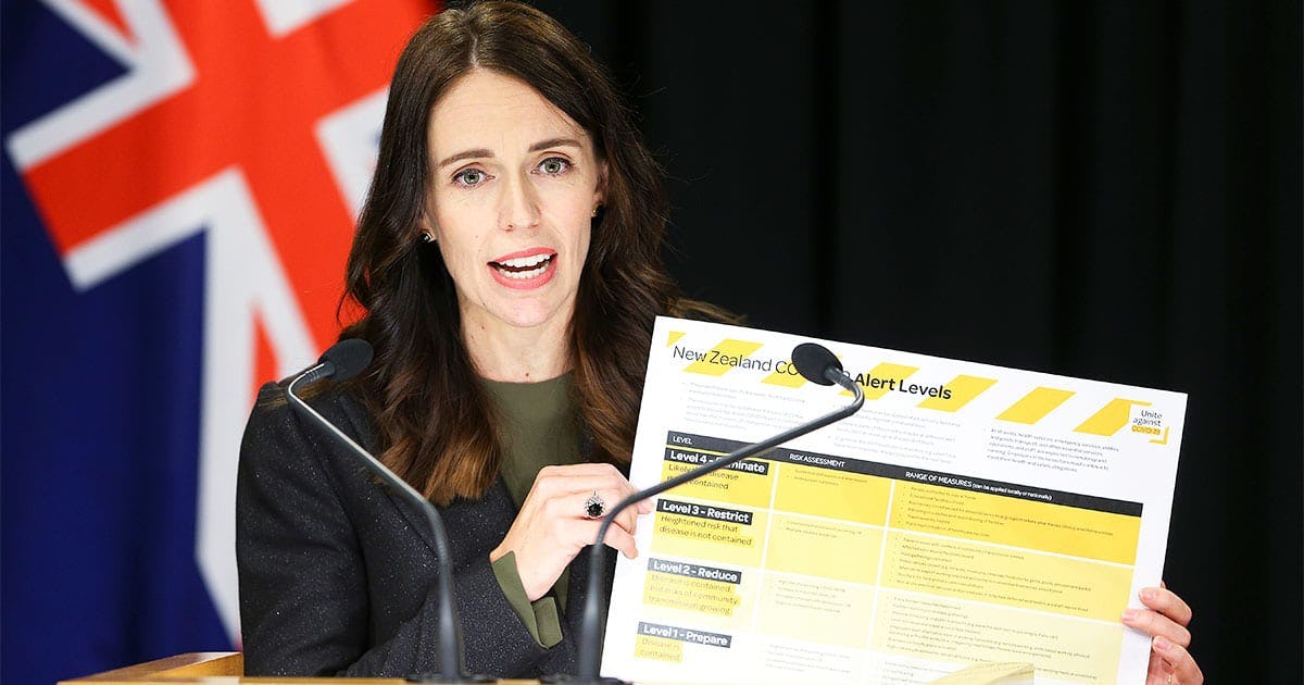 Prime Minister Jacinda Ardern holds up informationon COVID-19 alert levels