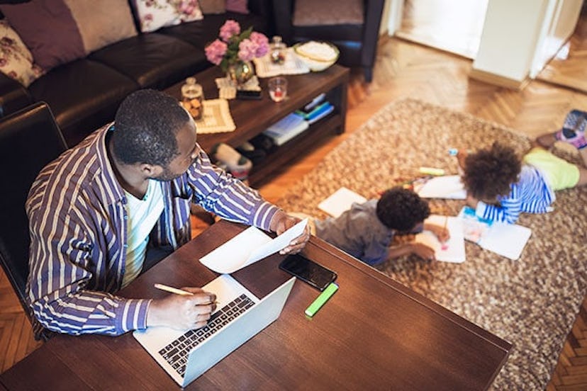 Father working from home while his two children are playing in the living room