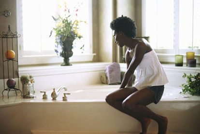 woman sitting on edge of bathtub