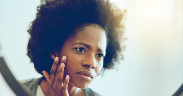 woman inspecting her face in the bathroom mirror