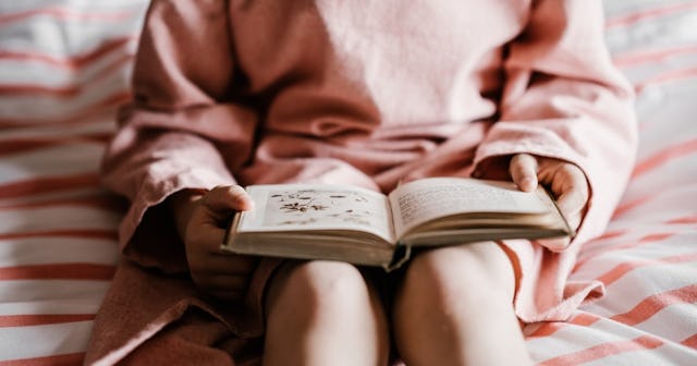linguistic intelligence, girl sitting reading a book in pink sweater