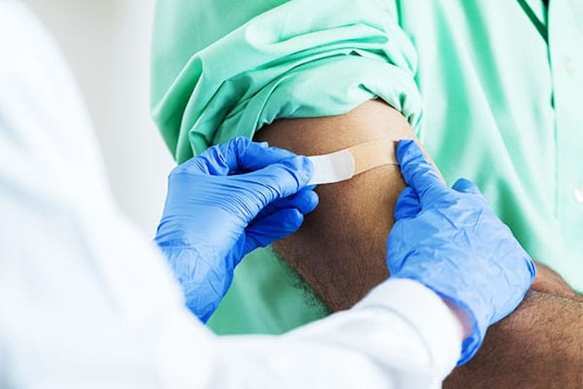 pharmacist placing bandaid on customer's arm