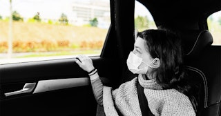 Young girl wearing mask looking through car window