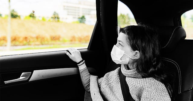 Young girl wearing mask looking through car window