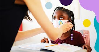 An elementary aged school student and teacher in a classroom wearing a mask for protection against i...