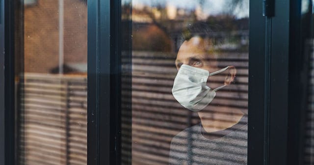 Study Shows Women Produce A Stronger Immune Response To COVID: Man with mask looking out of window