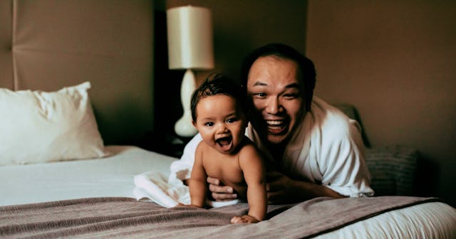 A man who became a single dad by surrogacy and his little baby lying on the bed and smiling