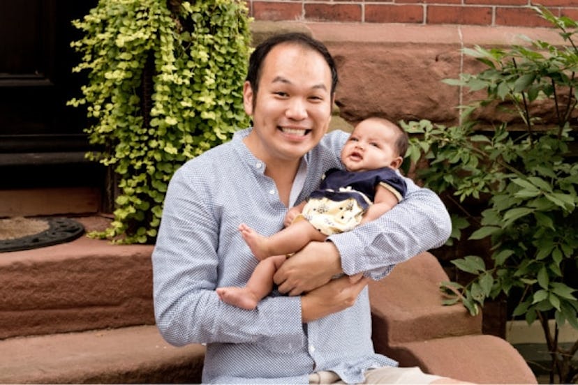 A man who became a singe dad by surrogacy, holding his little baby in his arms and smiling 