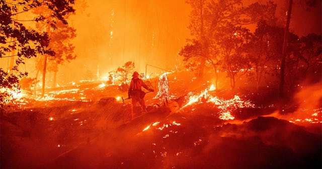 A firefighter works the scene as flames push towards homes during the Creek fire in the Cascadel Woo...