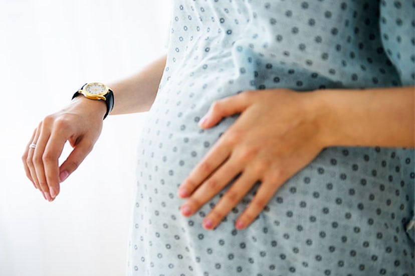 Pregnant woman wearing a blue patient gown with a black and gold watch on her right wrist