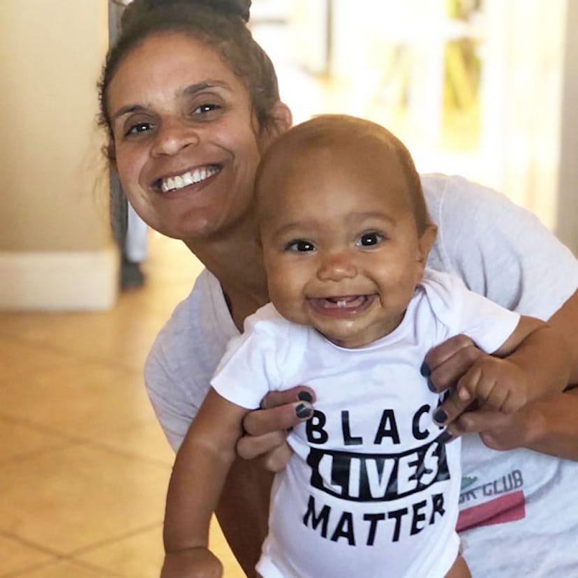 Leah Olson posing for a photo with her black-haired baby wearing a "black lives matter" white shirt