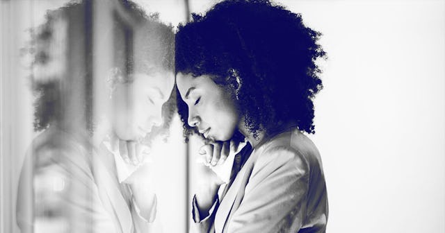 A curly-haired mom crying for her child leaned against the window, which shows her reflection