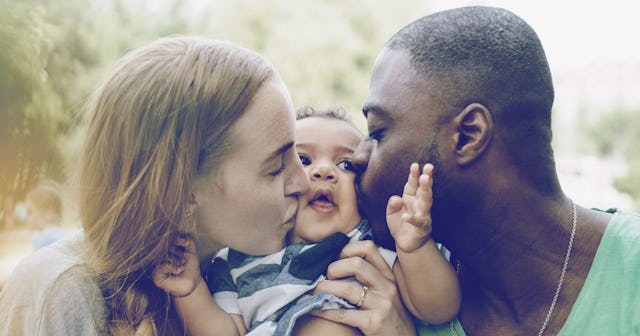 A man and a woman kissing their only child.