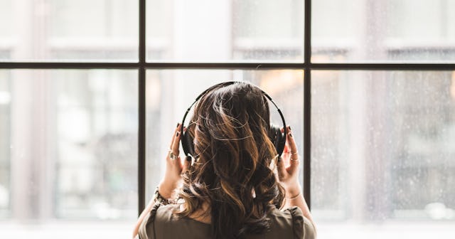 best grief podcasts, woman facing window with headphones on