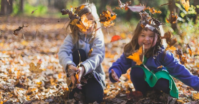 associative play, two girls playing in fall leaves