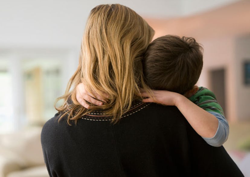 A boy with speech delay in his mom's arms with his head leaned on her shoulders 