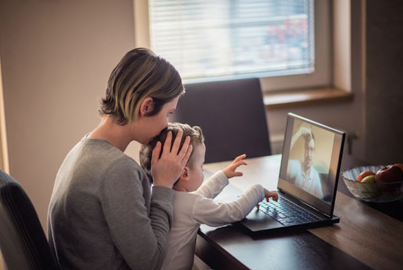 Mother and baby boy, toddler, talking with father on a Skype, using laptop, having family moment dur...