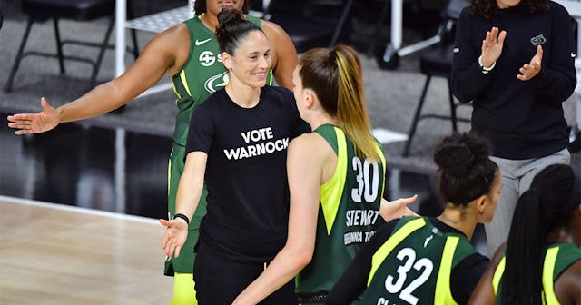 ue Bird #10 of the Seattle Storm low fives Breanna Stewart #30 while wearing a Vote Warnock T-shirt