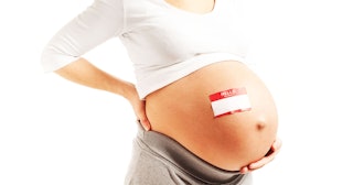 A woman with an exposed pregnant belly with a nametag on it