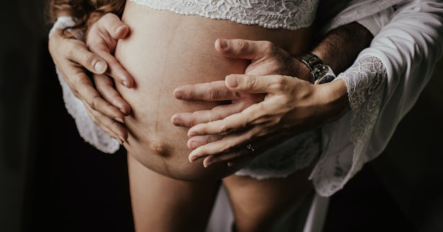 pregnant with man standing behind her clutching her abdomen in a non-threatening way