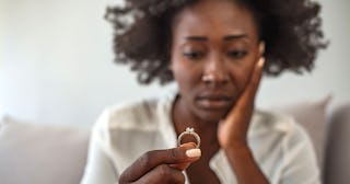 A divorced woman holding her ring and looking longingly at it.