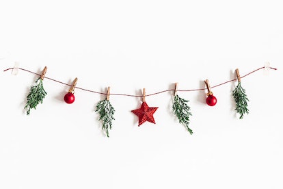 Christmas composition. Garland made of red balls and fir tree branches on white background. Christma...