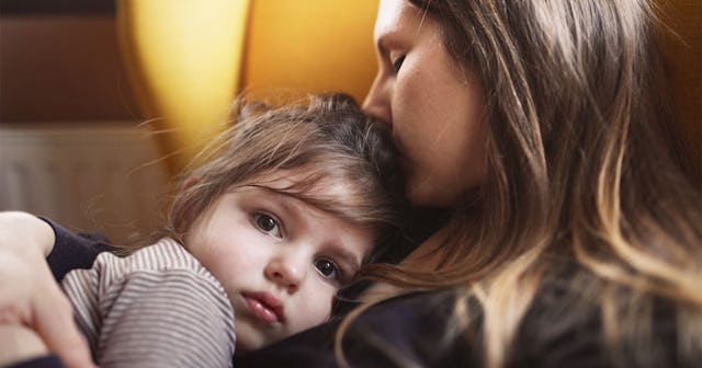 A mother holding and kissing her daughter