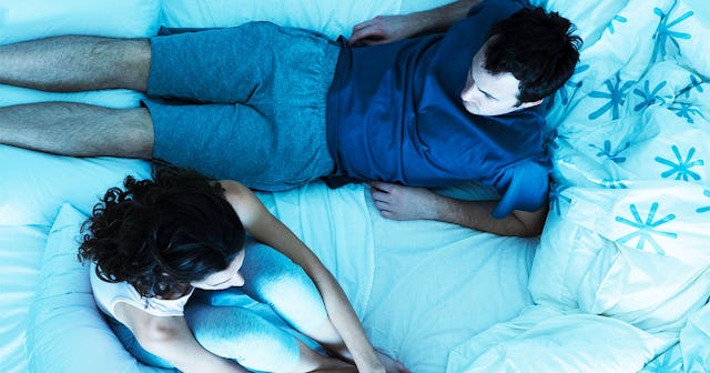 A man and a woman sitting on a bed