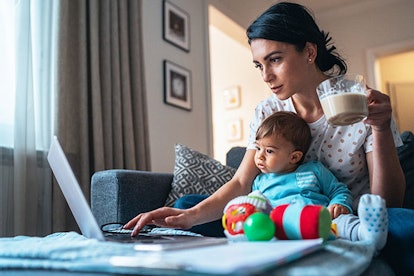 Young modern mother with a baby using laptop at home
