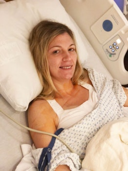 Megan Gill Carusona, who is battling breast cancer, smiling and lying in a hospital bed
