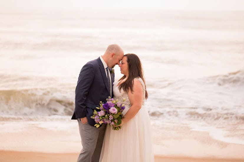 A couple posing next to sea on their wedding day