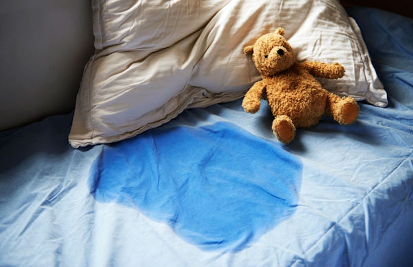 Dampened bed linens following an episode of bedwetting, accompanied by a teddy bear resting nearby.