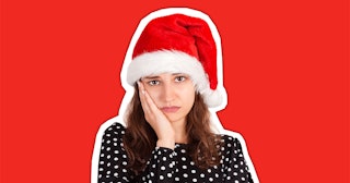A woman with brown hair wearing a polka dot top and a Santa hat, her cheek resting on her hand, look...