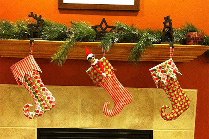 Christmas decorations - three colorful elf stockings hanging above the fireplace in a cozy setting