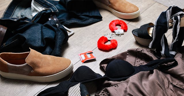 Male and female clothes and shoes on the floor across from each other with a condom wrapper and fluf...