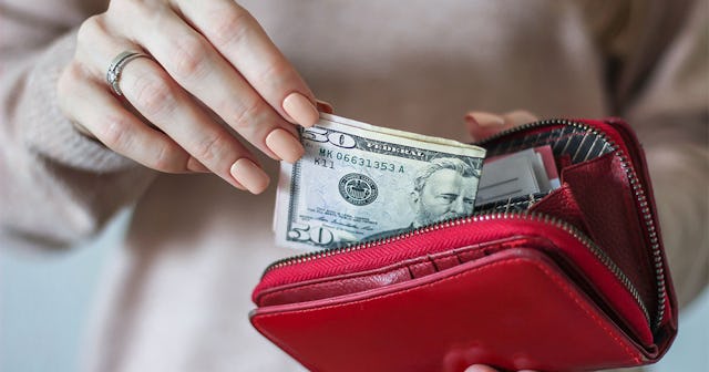 A woman putting money in a red wallet 