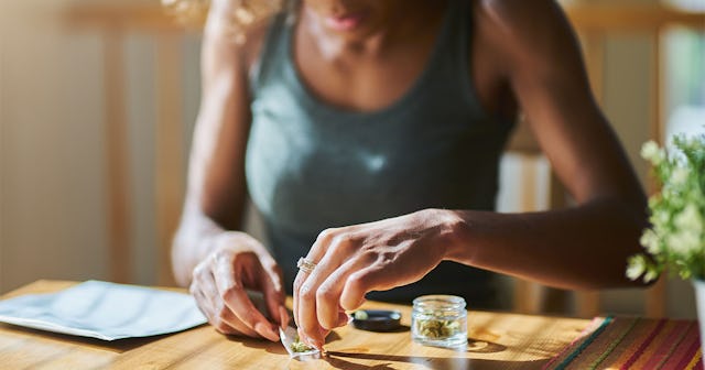 A woman sitting at a dining table and preparing cannabis to use it