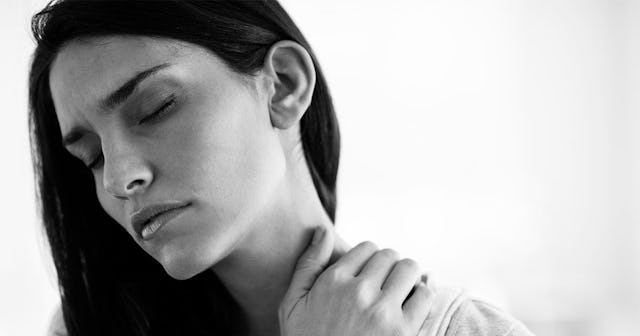 A woman with her hand on her neck in black and white