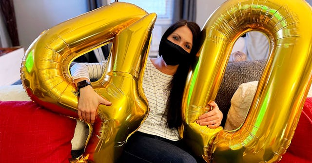 Stacy Seltzer holding her large golden 40th birthday balloons with a mask on her face