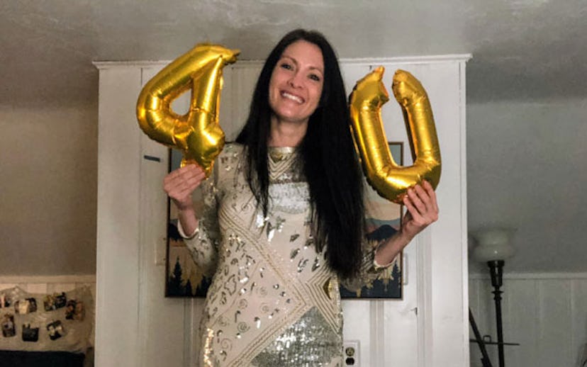 Stacy Seltzer holding her small golden 40th birthday balloons with a mask on her face