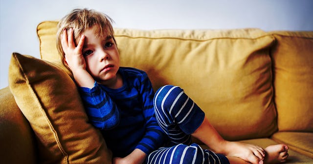 An exhausted little boy sitting on a couch