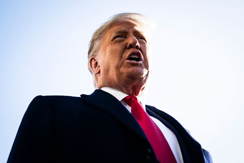 Politician Donald Trump wearing a black suit and a red tie talking 