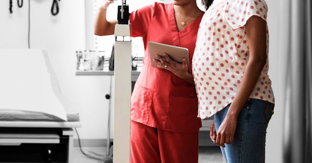 Nurse weighing pregnant woman in hospital room