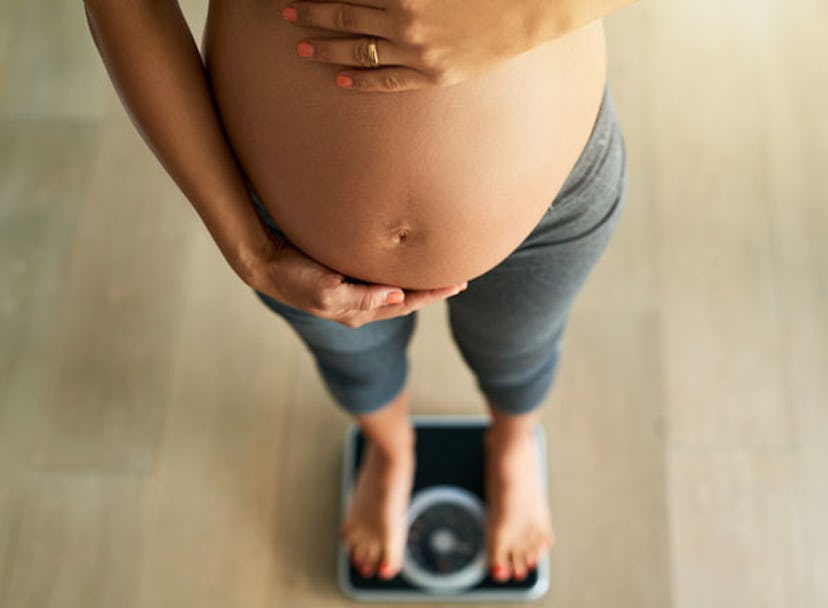 Cropped high angle shot of a pregnant woman weighing herself on a scale