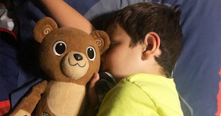 A boy with Type 1 Diabetes laying in bed with his teddy bear 